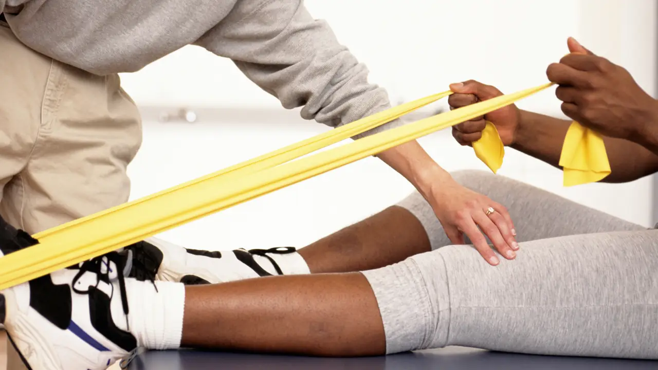 Physiotherapist using a resistance band to treat a patient's leg