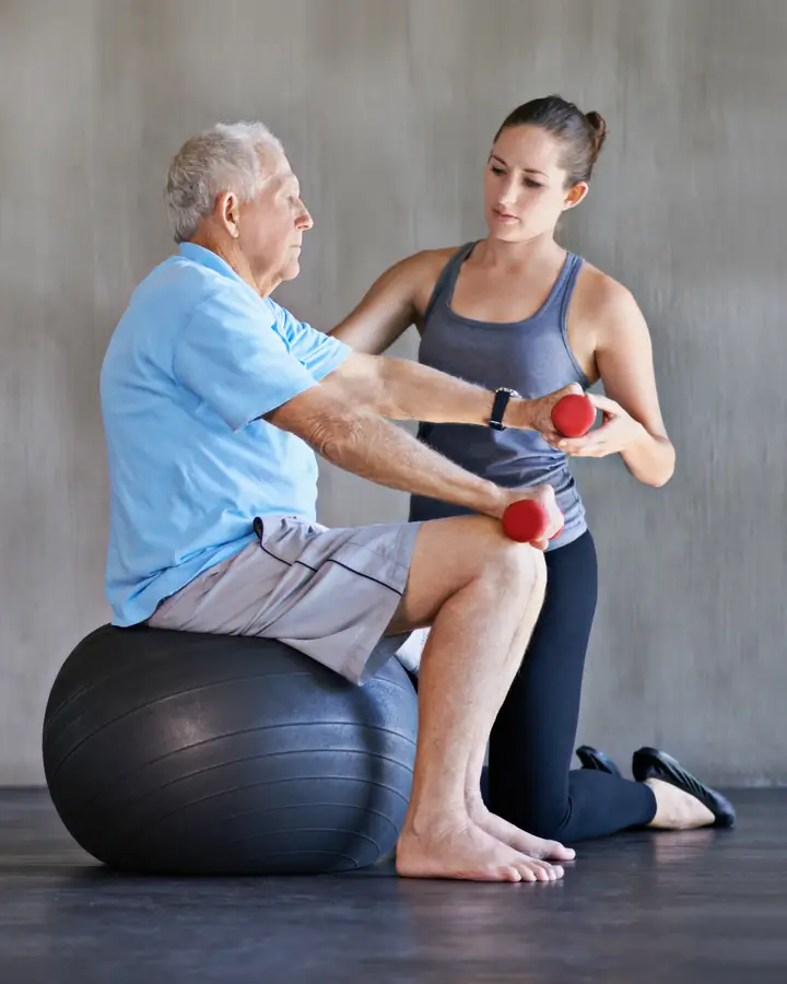 Physiotherapist guiding an older patient through strengthening exercises